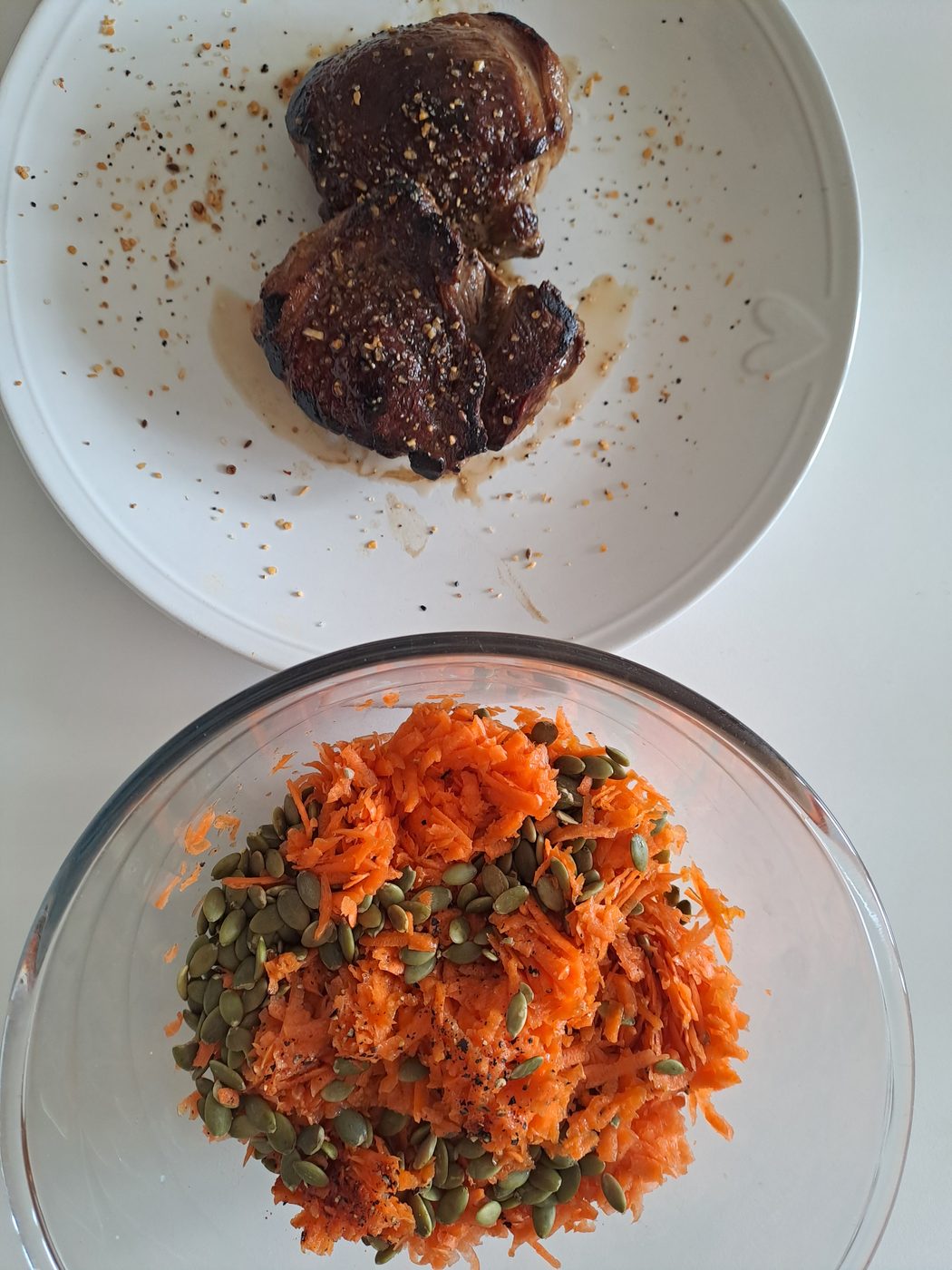 Grated carrot salad with pumpkin seeds next to fried lamb