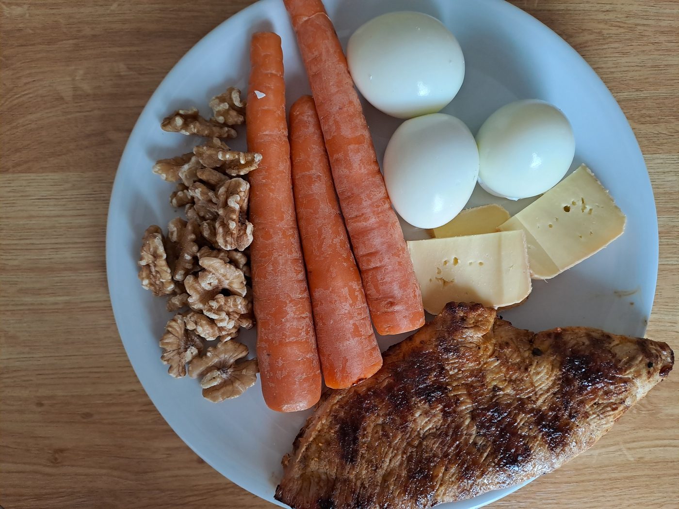 Grilled turkey breast with carrots, boiled eggs, walnuts and local raw milk cheese on a plate