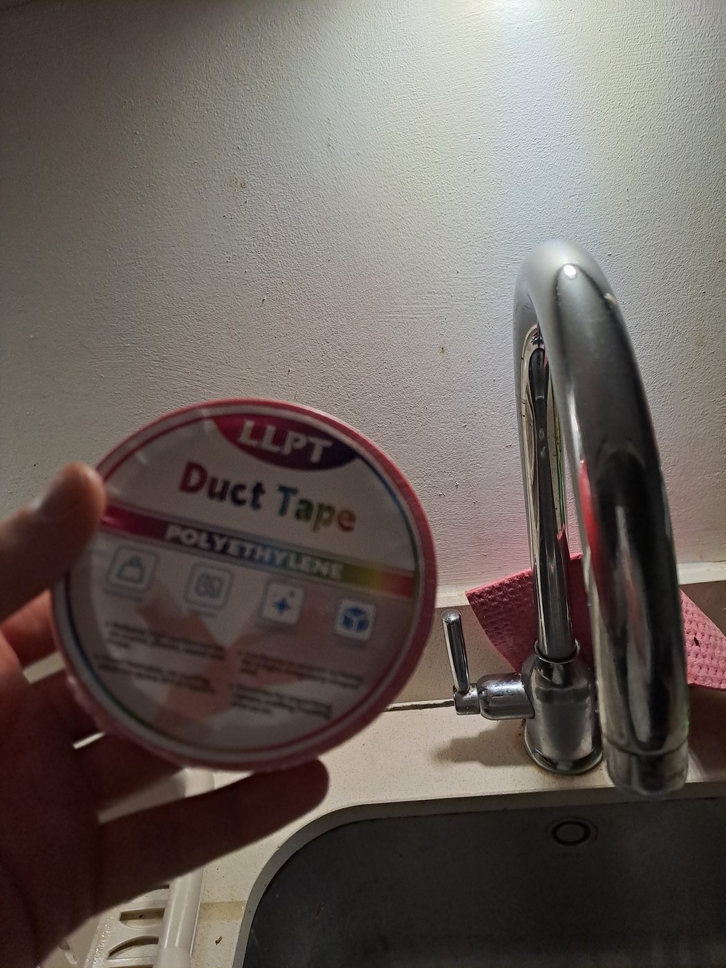 A roll of red polyethylene duct tape held up in the kitchen