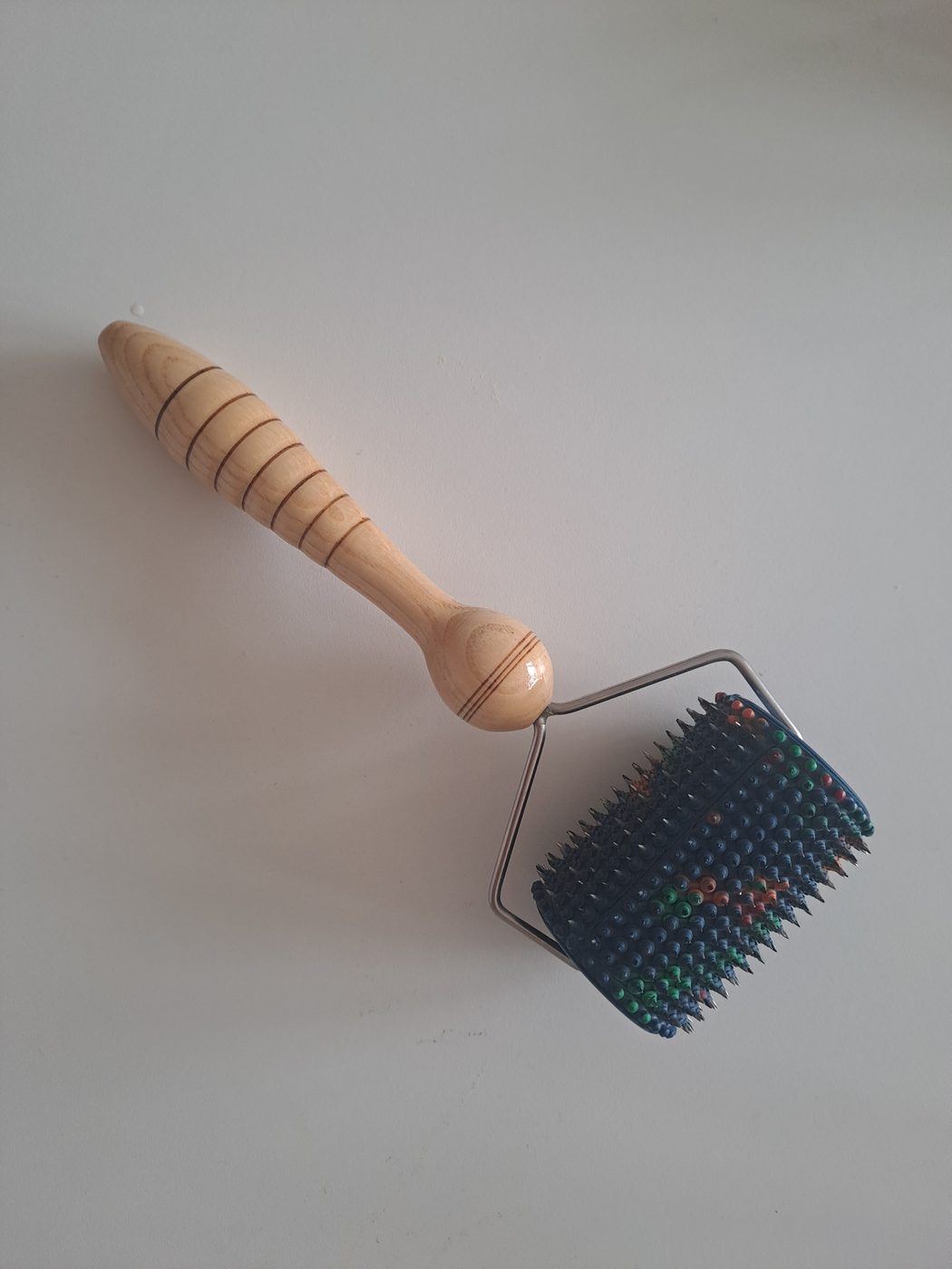 A wooden acupressure roller with a spiked head