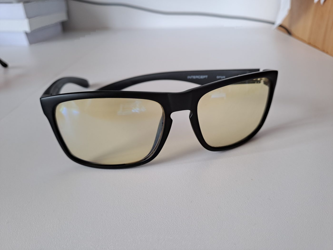 Black glasses with amber lenses on a white desk