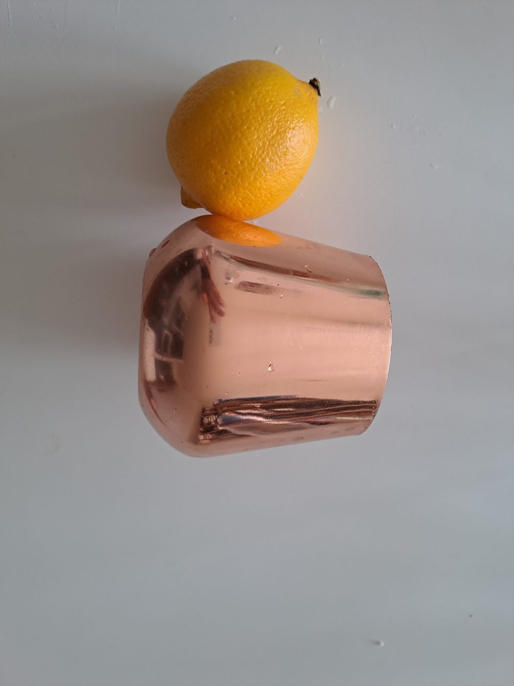A copper drinking cup with a fresh lemon balanced on top