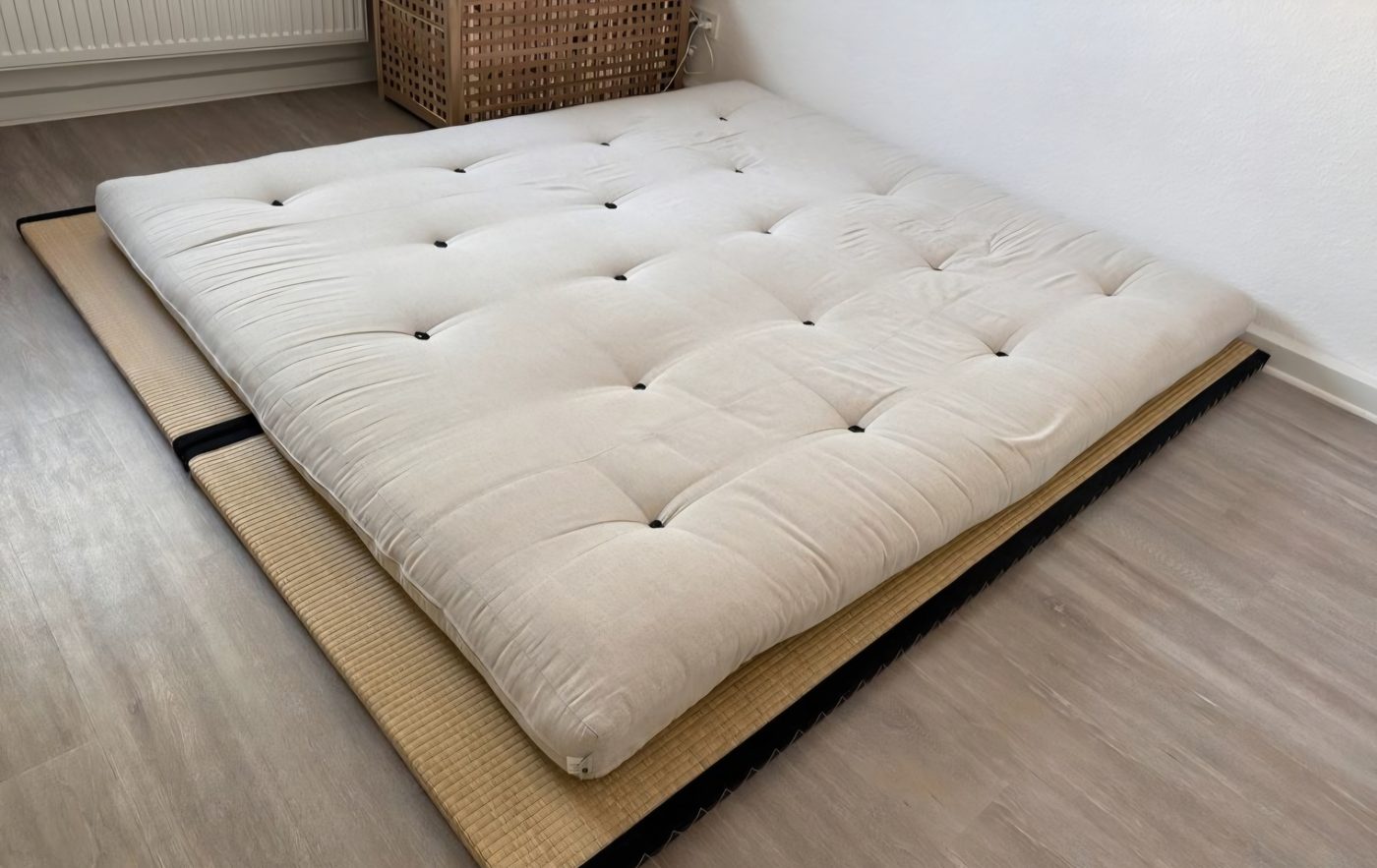 A natural futon mattress laid on a tatami mat on the floor