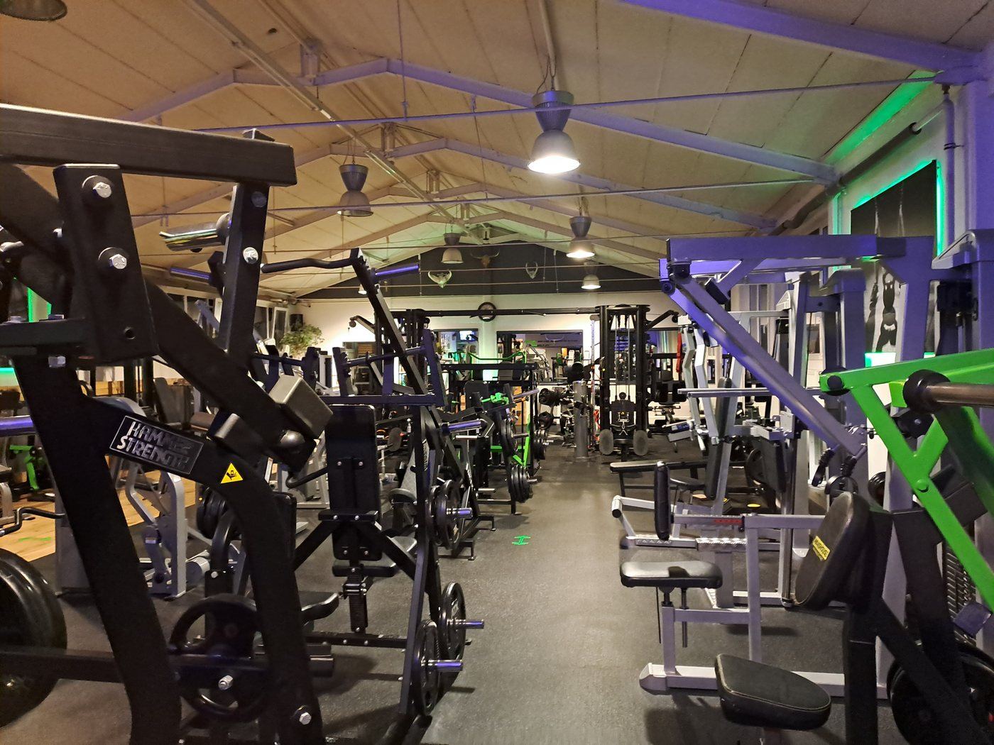 Inside a well-equipped gym at night with rows of machines and free weights