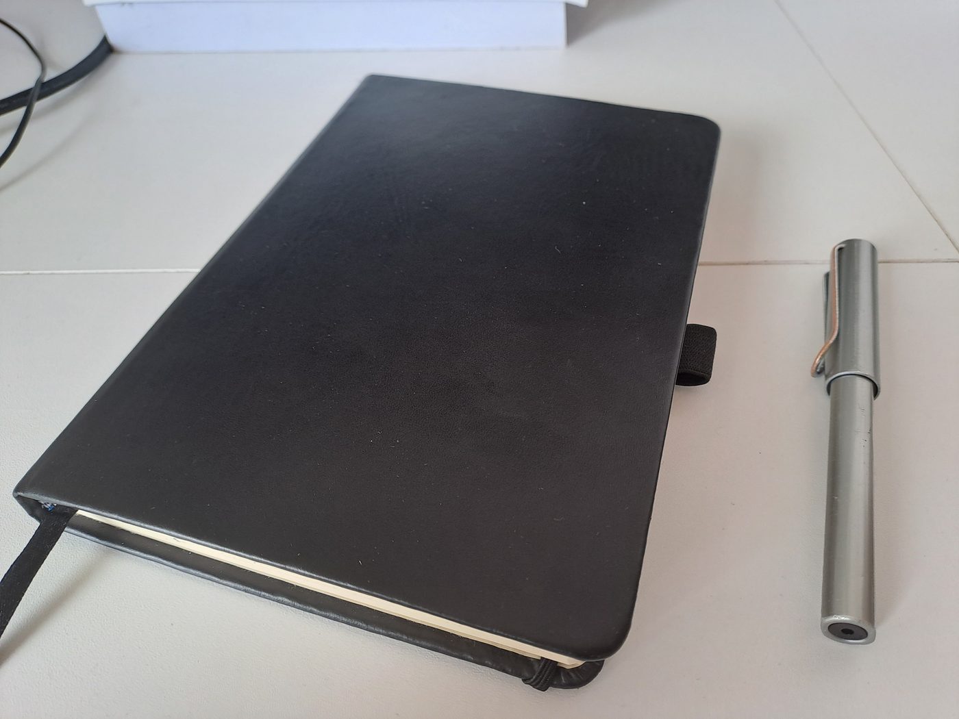 A black hardcover journal with an elastic band and a fountain pen beside it