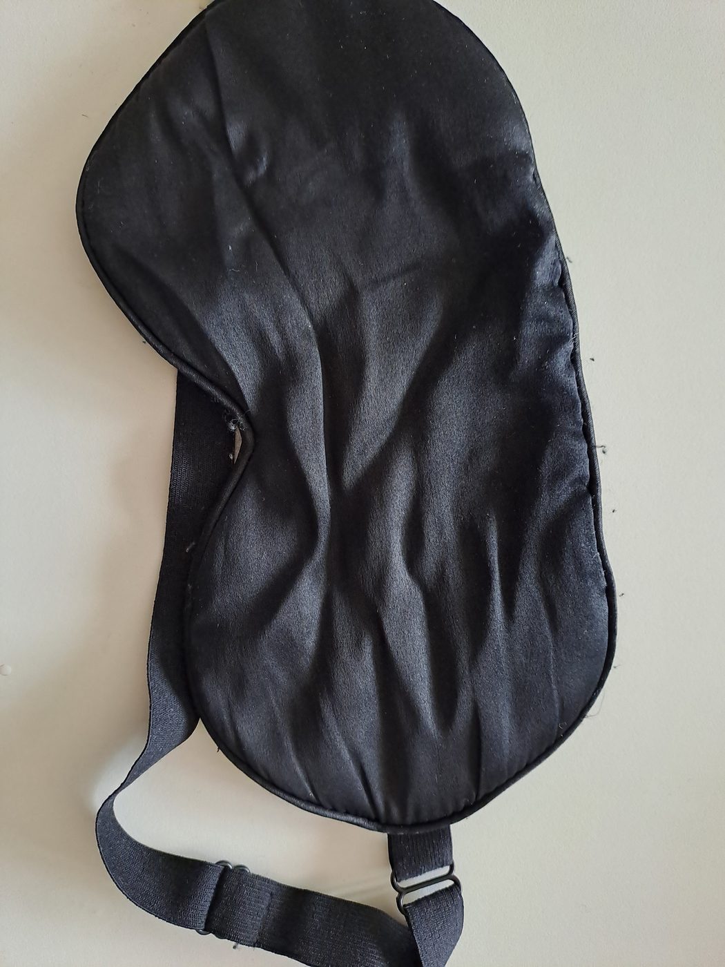 A black silk sleep mask with an adjustable strap