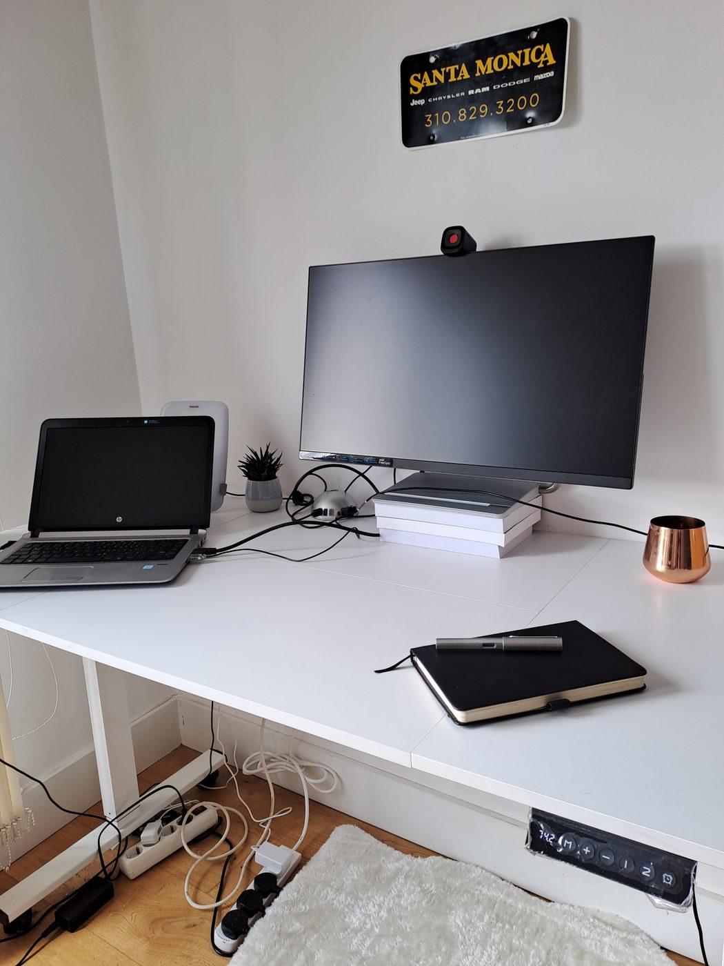 A height-adjustable standing desk with laptop, monitor and journal