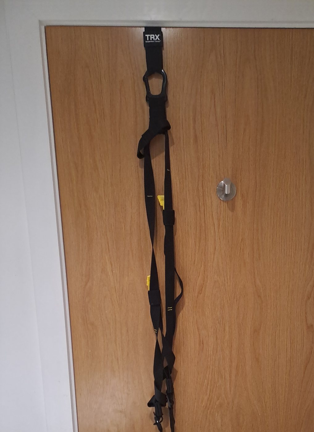The TRX suspension trainer hanging from the top of a door, ready to use
